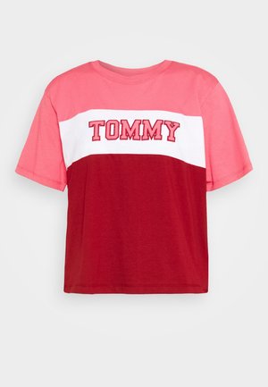 Camiseta de manga corta en bloque de colores rojo y rosa con una franja blanca; presenta "TOMMY" en letras bordadas en negrita a lo largo del pecho.