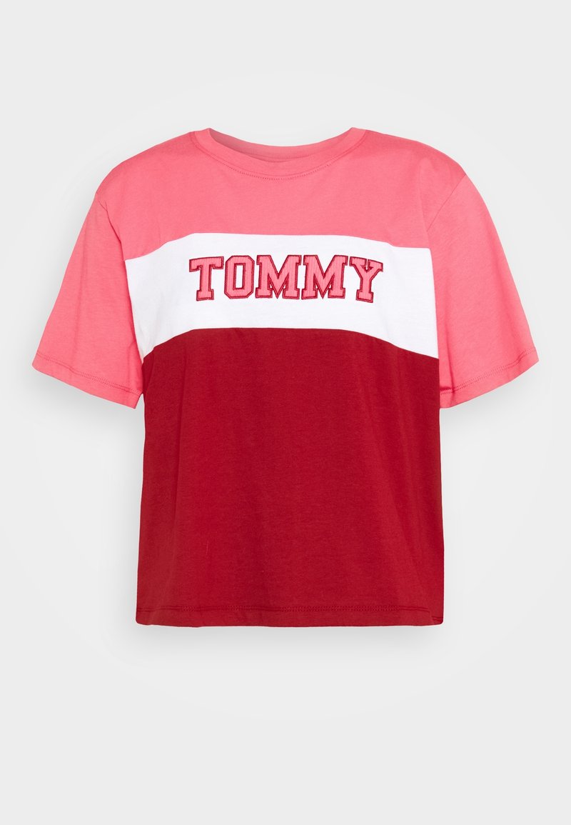 T-shirt à manches courtes coloré en rouge et rose avec une bande blanche ; arbore "TOMMY" en lettres brodées en gras sur la poitrine.