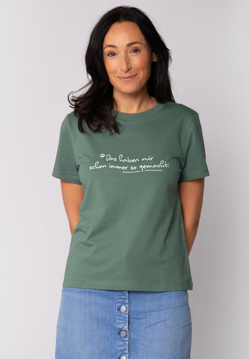Groen katoenen t-shirt met korte mouwen en een ronde hals, met witte tekst gedrukt over de borst. Gladde textuur en casual pasvorm.