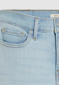 Jeans de mezclilla azul claro con un diseño clásico de cinco bolsillos, costuras en contraste de color naranja y un cierre de botón de metal plateado.