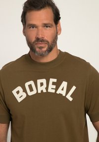Olivově zelené tričko vyrobené z hladké bavlny, s výrazným bílým nápisem "BOREAL" na hrudi, krátké rukávy a kulatý výstřih.