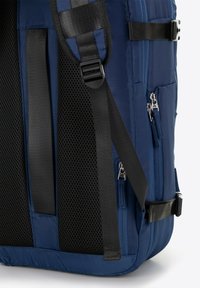 Marineblauwe rugzak met mesh-padding op de banden, ritszakken en zwarte verstelbare hardware. Glad materiaal met een gestructureerde vorm.