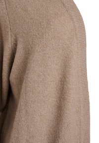 Beige neulepaita, jossa on tekstuuripinta, ribbireunukset ja pehmeä, kevyt materiaali. Kuvassa neljännesnäkymä.