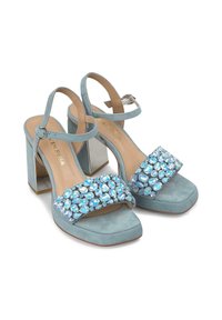 Sandali con tacco alto in suede azzurro chiaro, con punta quadrata, decorati con grandi cristalli azzurri su una larga fascia e un tacco a blocco metallico.