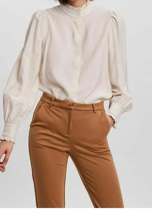 Witte blouse met pofmouwen en een gerimpelde kraag, gecombineerd met bruine, op maat gemaakte broek met zijzakken en een gladde textuur.