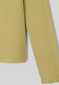 Top à manches longues, col rond en coton jaune muet. Présente une finition texturée et un ourlet légèrement effiloché au niveau des poignets.