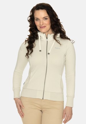Felpa zip con cappuccio di colore beige chiaro realizzata in tessuto morbido, con colletto alto, cappuccio con cordino e una silhouette aderente. Tasche laterali opzionali.