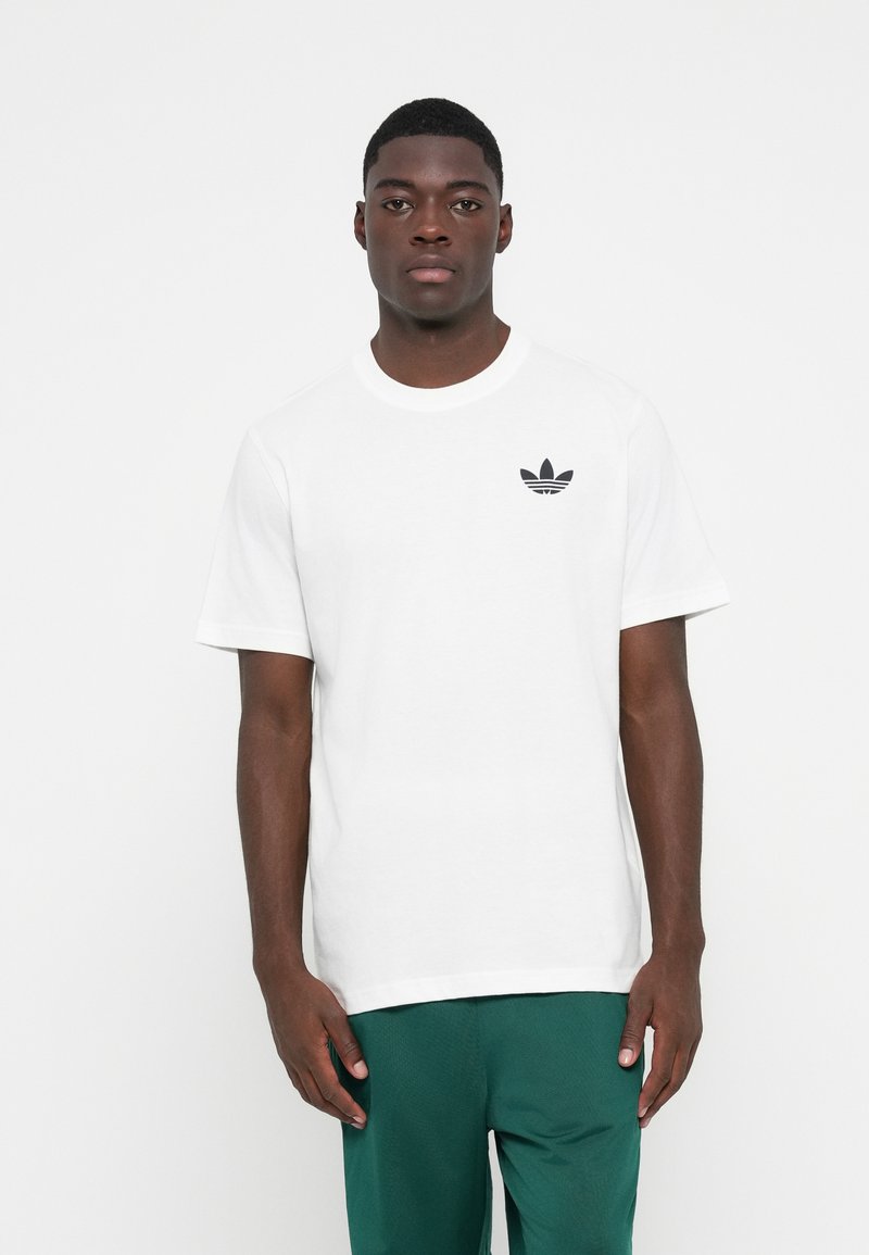 Hvid bomulds T-shirt med et lille sort Adidas-logo på venstre bryst. Korte ærmer og en rund halsudskæring med en klassisk pasform.