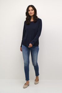 Sötét tengerészkék, hosszú ujjú felső, lekerekített nyakkivágással, világoskék, slim fit farmernadrággal és bézs balerinacipőkkel párosítva. Simaság és kényelmes fazon jellemzi.