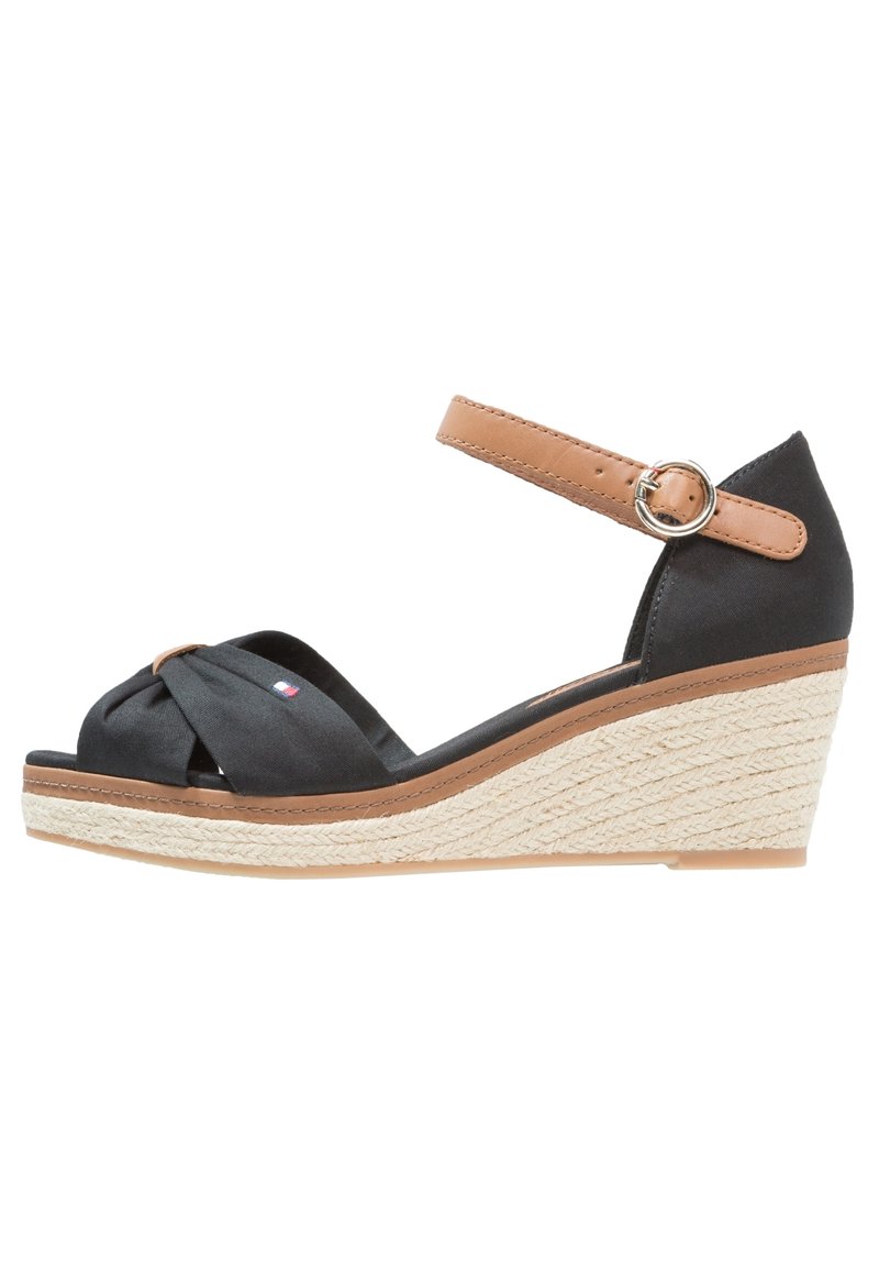Sandale compensée noire avec semelle espadrille tissée, bride de cheville marron clair avec boucle argentée et bride avant torsadée avec petit détail logo.