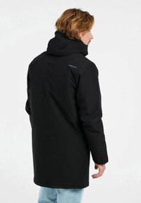 Cappotto nero con cappuccio e vestibilità rilassata. Presenta un tessuto morbido, maniche lunghe e un design semplice. Logo sul retro vicino al collo.