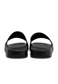 Black sandals with a flat sole and open design. Features a smooth texture and two curved straps across the top for stability.