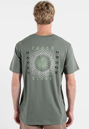 T-shirt en coton vert kaki avec un motif graphique en spirale blanc et vert au dos, accompagné du texte "Ocean Vibes" en police épaisse.
