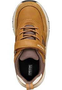 Zapatilla de cuero marrón y gamuza con una correa de Velcro, forro de tejido texturizado y una entresuela blanca con una suela de goma negra.