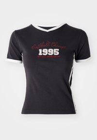 Melnas kokvilnas T-krekls ar īsām piedurknēm, baltu apdari un vintage stila uzrakstu "Softball Champ 1995" sarkanā un baltā krāsā.