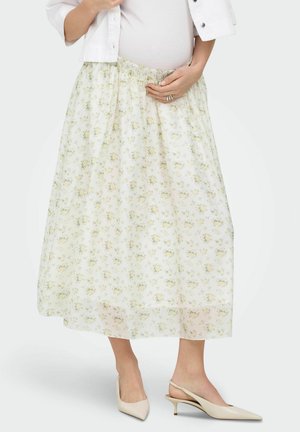 Osoba w ciąży nosząca białą kwiecistą spódnicę midi, jasny top, białą krótką kurtkę i beżowe slingbacki na niskim obcasie.