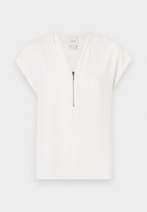 Hvit kortermet topp med V-hals og sølvglidelåsdetalj foran, laget av glatt, lett stoff. Minimalistisk design.
