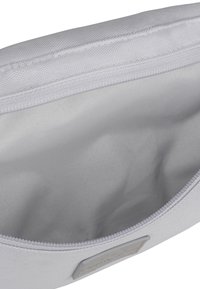 Pochette bianca con zip, dotata di un esterno testurizzato e un interno liscio. Presenta una discreta etichetta con logo e cuciture solide lungo le giunture.