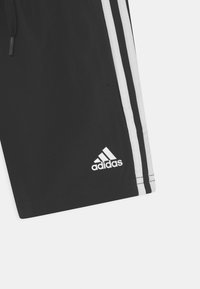 Black athletic shorts with white striped side accents. Features an elastic waistband with a drawstring and a small white Adidas logo.