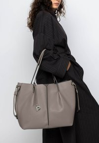 Grijze lederen tote bag met een textuurafwerking, voorzien van dubbele handvatten, een zilveren logo accent en verstelbare trekkoordzijden.