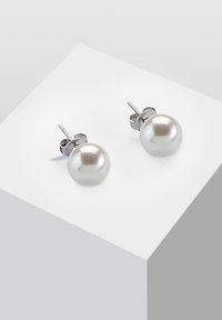 Orecchini a perno in argento che presentano grandi perle bianche lucide e rotonde con una texture liscia. Design semplice con hardware minimale.