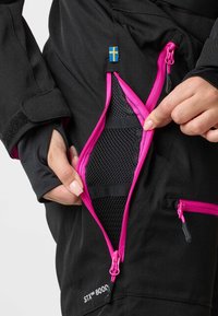 Black waterproof ski pants with bright pink zippers. Zipper reveals mesh lining and elastic straps. Includes a Swedish flag detail.