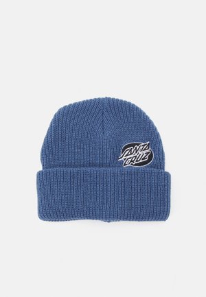 Kék kötött sapka hajtott mandzsettával. Elöl egy fehér "Santa Cruz" logóval ellátott folt található. A texturált fonal melegen tart és kényelmet biztosít.