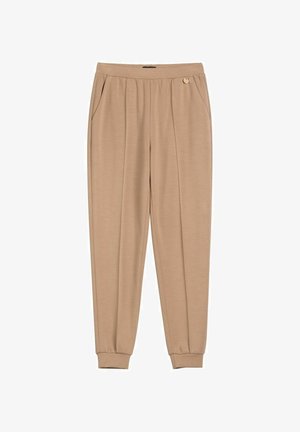 Beżowe, zwężane spodnie z elastycznym pasem, bocznymi kieszeniami, małym detalem w postaci guzika oraz elastycznymi mankietami.