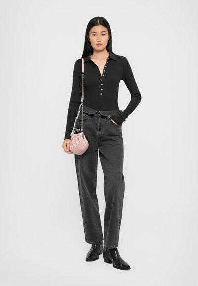 Black long-sleeve polo top with button detail, paired with high-waisted gray denim jeans. A pink textured handbag with a chain strap is held.