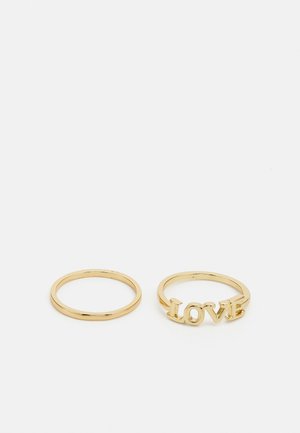 Sæt af ringe i guldtonet metal, der inkluderer en enkel ring og en ring med ordet "KÆRLIGHED" i udskårne bogstaver. Glat overflade, poleret finish, slank design.