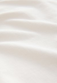 White cotton fabric with a smooth texture, showing gentle folds and a subtle sheen, emphasizing its lightweight and breathable quality.