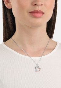 Silver heart necklace featuring a dual-tone design with rose gold accents and small embedded gems, hung on a thin chain.