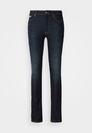 Dark blue denim jeans with a slim fit, featuring a classic five-pocket design, button closure, and subtle fading on the thighs.