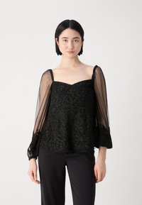 Schwarzes besticktes Oberteil mit transparenten Glockenärmeln, strukturiertem Stoff und tailliertem Mieder. Komplexe Perlendetails verleihen Tiefe und Eleganz.