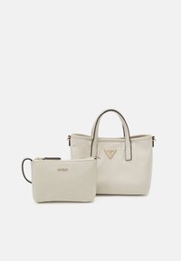 Petit sac à main beige avec deux petites poignées et une pochette beige assortie zippée avec une sangle pour poignet, tous deux ornés de logos de marque dorés.
