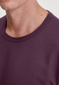 Paars T-shirt met korte mouwen en een ronde hals, gemaakt van zachte katoenen stof, met een gladde textuur en minimale stikseldetails.
