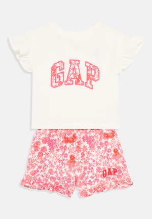 Conjunto de duas peças composto por um top de manga curta branco com "GAP" em impressão floral rosa e calções florais rosas com bainha em babados e detalhe do logo.