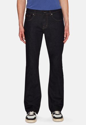 Mørkeblå denimjeans med lige ben, kontrastsyninger, fem lommer og knaplukning, parret med sorte og hvide sneakers.