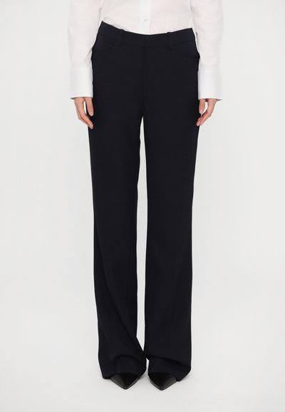Pantaloni negri ajustați, cu o textură netedă, design cu picioare largi și buzunare laterale. Asortați cu o cămașă albă cu nasturi și pantofi cu toc ascuțit negri.
