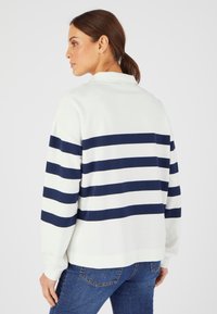 Suéter blanco con rayas horizontales en azul marino, cuello con solapa y mangas largas. Tejido suave y ligero, ajuste relajado.