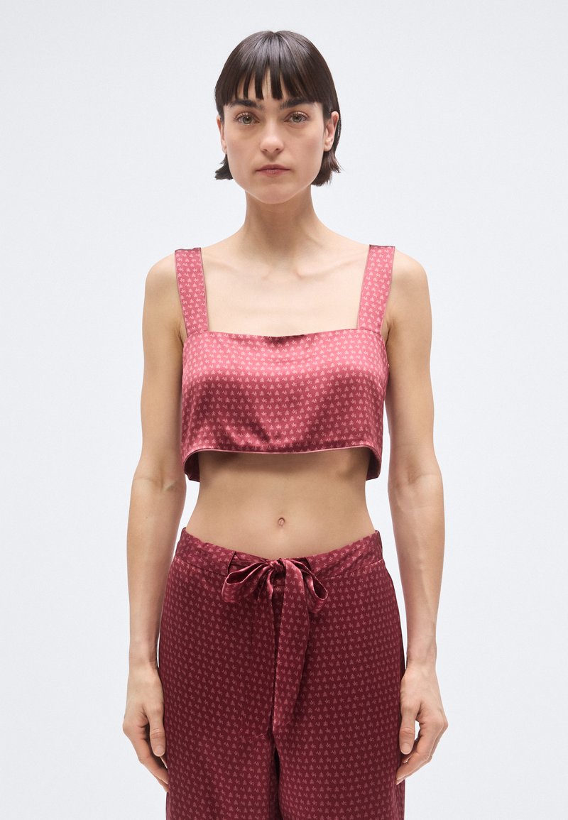 Burgundia lühendatud topp, tehtud siledast, läikivast kangast, kandilise kaelusega ja laiade rihmadega, millel on kogu ulatuses väikesed geomeetrilised mustrid.