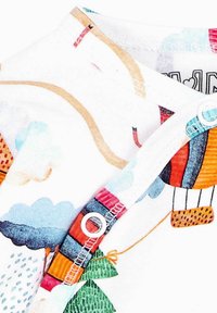 Hvid bomuldsstof med farverige illustrationer af luftballoner, skyer og træer; har trykknapper ved halsudskæringen og en glat tekstur.