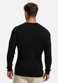 Schwarzer Strickpullover mit strukturiertem Zopfmuster, Rundhalsausschnitt und langen Ärmeln. Enganliegendes Design mit gerippten Bündchen und Saum.