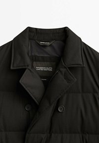 Giubbotto in nylon nero con colletto, bottoni doppi e una consistenza liscia con leggero imbottitura, etichettato come "Edizione Limitata Massimo Dutti."