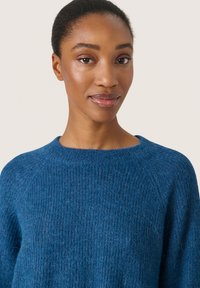 Maglione blu a maglia con scollo rotondo, tessuto testurizzato e vestibilità comoda. Presenta maniche raglan e piccole ami per un tocco di dettaglio in più.