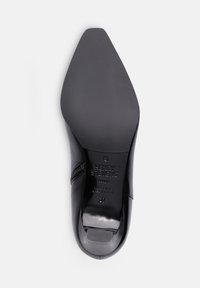 Semelle de chaussure à talon haut en cuir noir avec un bout pointu, surface texturée, branding en relief, taille 37, section de talon lisse. Base de chaussure plate.
