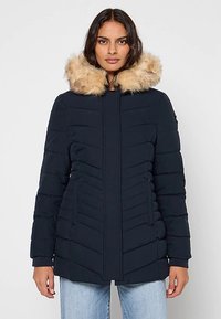 Granatowa kurtka puchowa z kapturem obszytym futrem, pionowymi paskami oraz dwoma bocznymi kieszeniami, zapinana na zamek, z lekko teksturowanym wykończeniem.