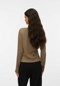 Langermet topp i olivengrønn, laget av glatt stoff. Designet har rund hals og en innsvingt silhuett, kombinert med svarte bukser.