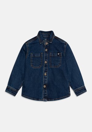 Mørkeblå denimjakke med spiss krage, knappelukking, to brystlommer og kontraststikking.