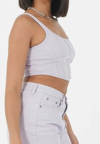 Top corto de color púrpura claro con relieve y tirantes delgados, con detalles en costura vertical. Combinado con pantalones de talle alto a juego.